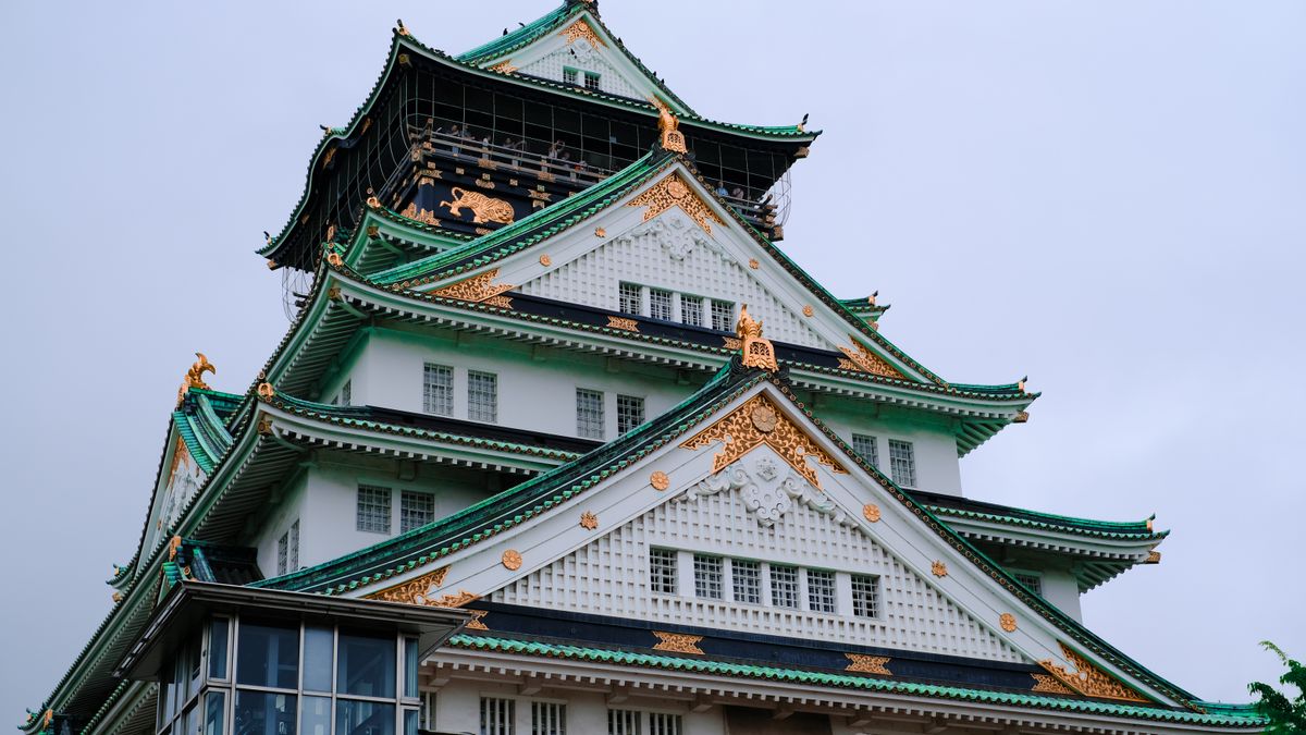 오사카 — Majestic view of Osaka Castle showcasing classic Japanese architecture against a clear sky.