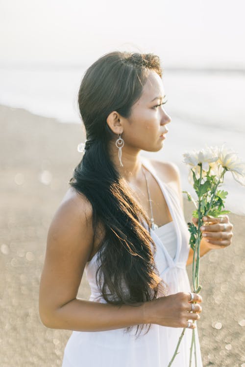 Woman Holding Flower Standing on Seashore