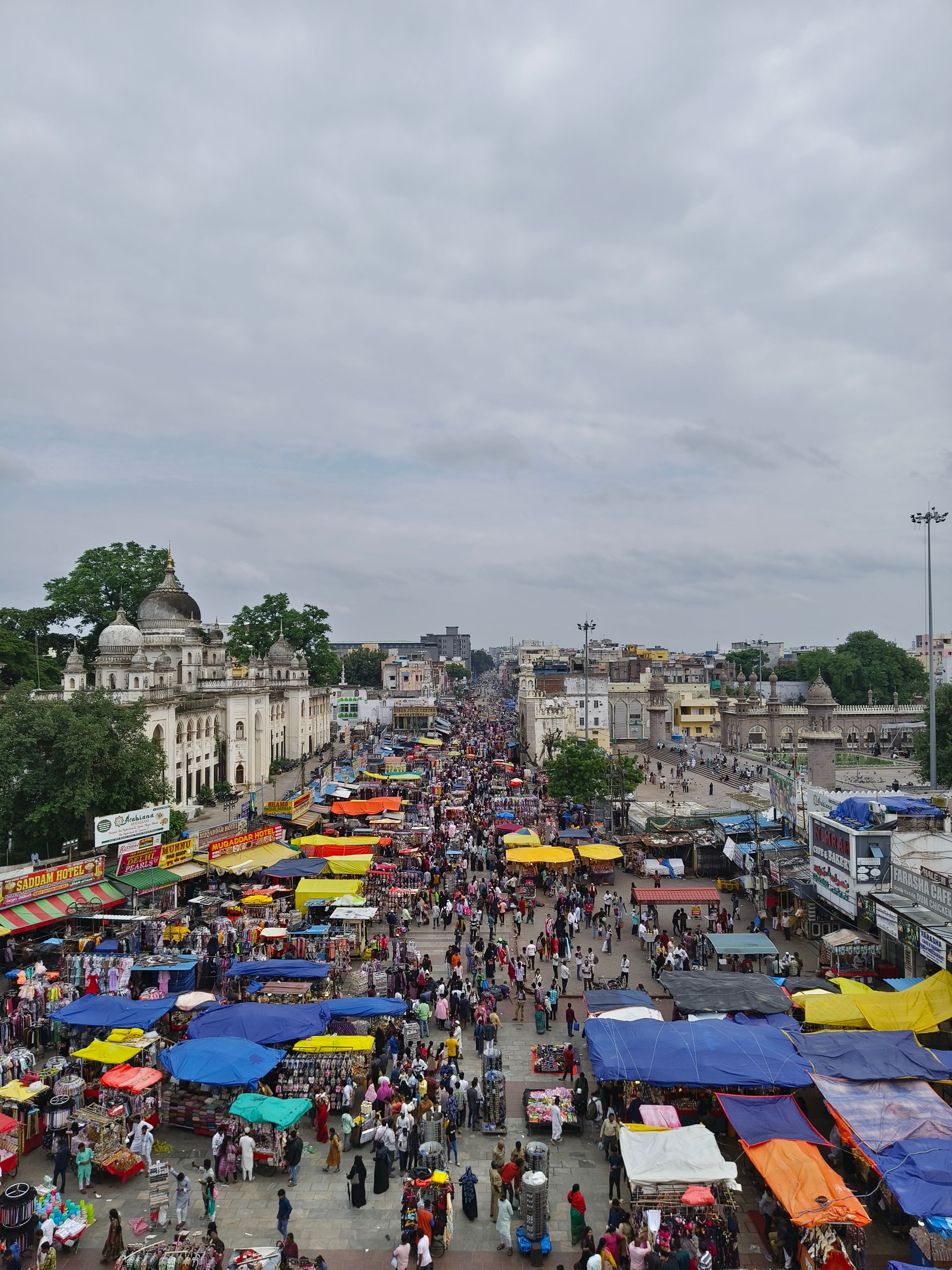 Vibrant outdoor market in Hyderabad, India with colorful stalls and a busy crowd.