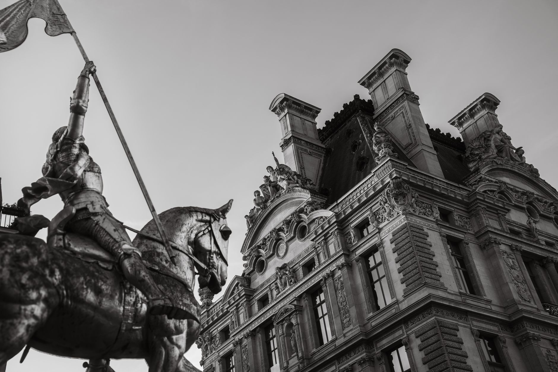 Black and white photo of baroque architecture and equestrian statue in Paris, France.