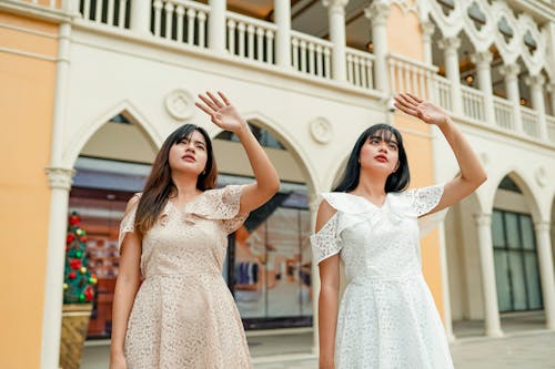 Two Women Standing Near White Building