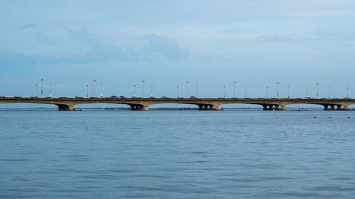 Free A minimalist view of a bridge extending over calm waters under a clear blue sky. Stock Photo