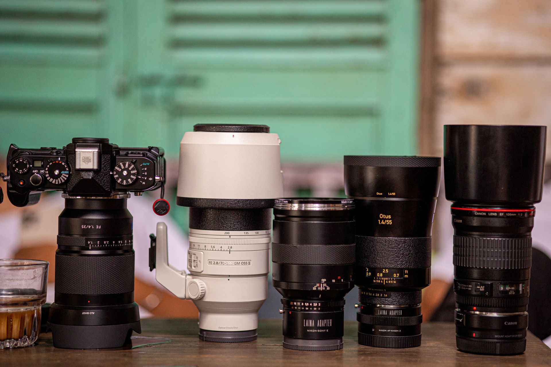 Diverse camera lenses and a vintage camera arranged on a table with a coffee ambiance.