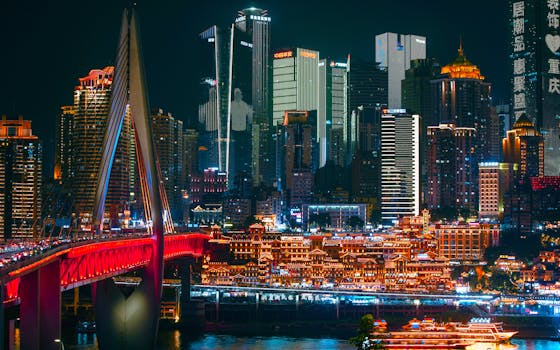 Vibrant nighttime view of Chongqing's illuminated skyline and bridge reflecting on the river.