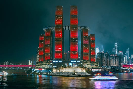 Illuminated skyscrapers reflecting in the river, showcasing Chongqing's modern cyberpunk skyline.