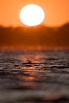 Serene view of sunset above peaceful water surface with warm glow.