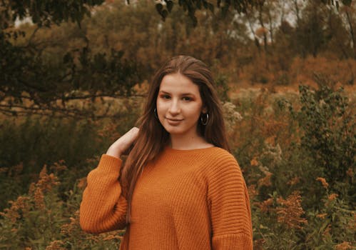一位年轻女子身着针织毛衣，置身于舒适的秋日景致中