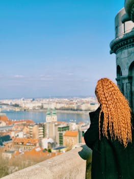 Woman with orange hair admiring Budapest's skyline and Danube River.