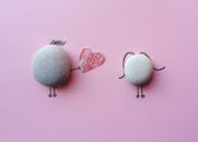 粉红色背景上带有心脏象征的迷人石头艺术品，寓意着爱与联系