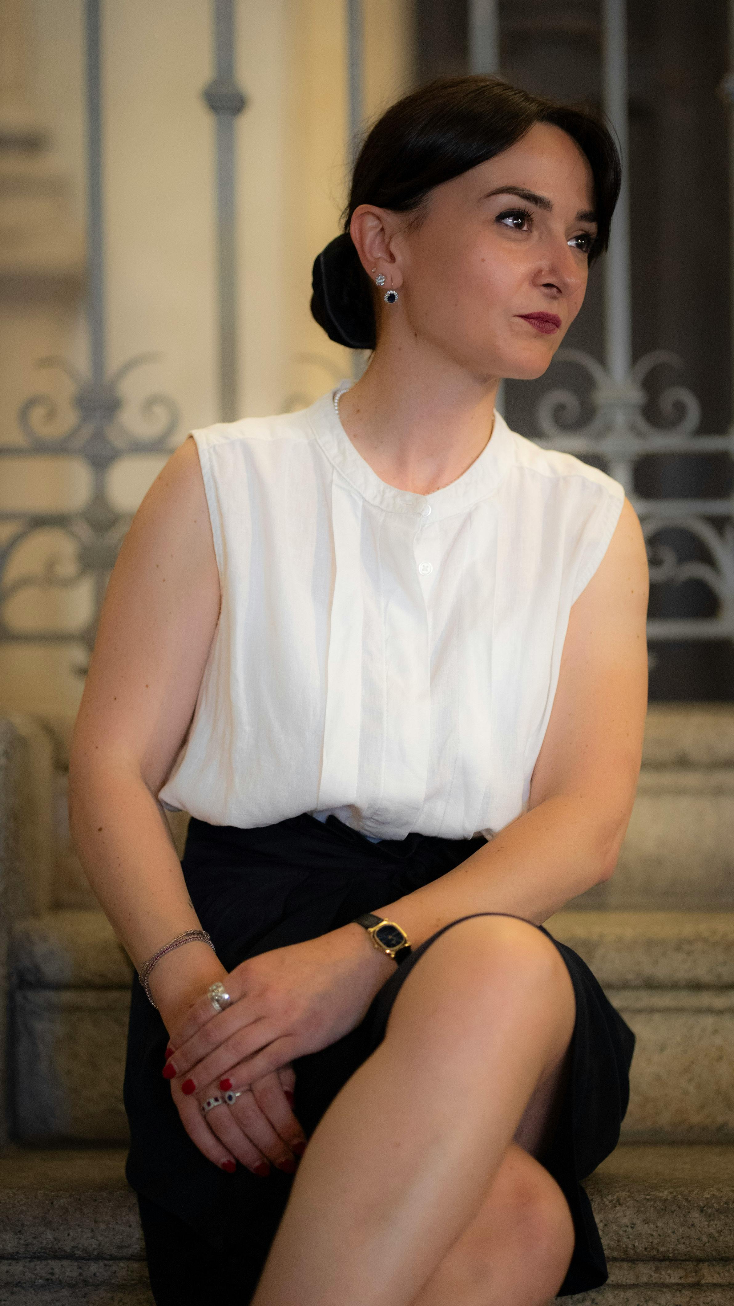 Stylish woman sitting elegantly on stairs in Milan, showcasing fashion and grace.