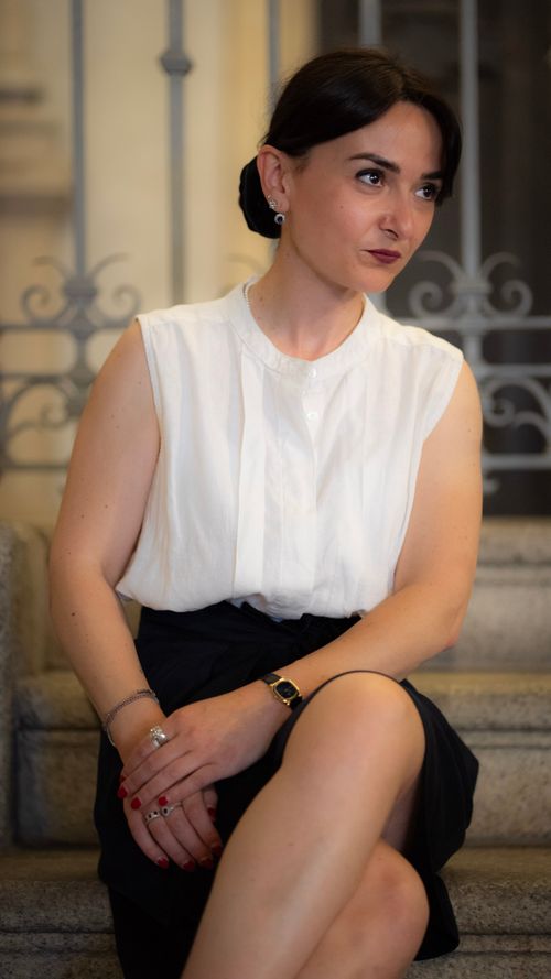Free Stylish woman in elegant attire seated on steps, showcasing fashion in Milan. Stock Photo