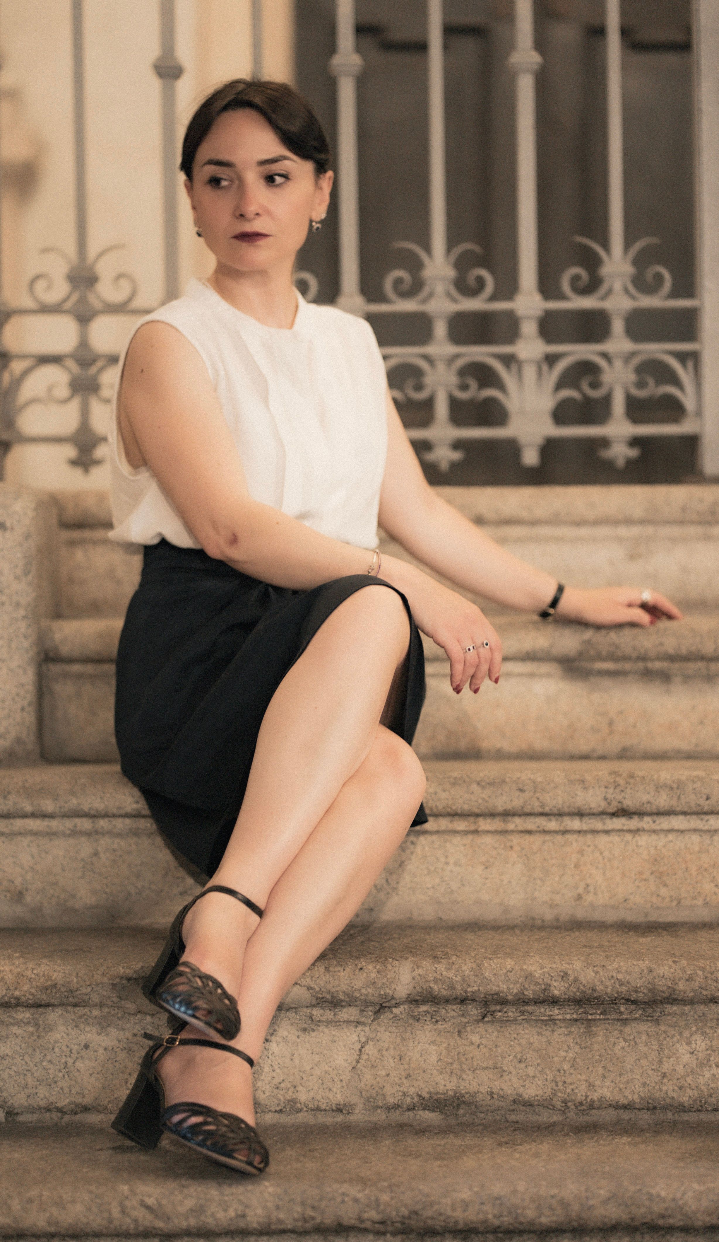 A stylish woman elegantly posing on stone stairs in central Milan, showcasing classic fashion.