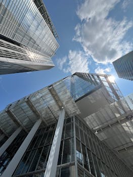 Dynamic view of towering modern skyscrapers reaching into a bright blue sky.