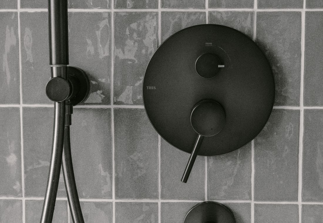 Modern black shower head and controls installed on bathroom tile