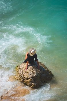 A person relaxing on a rock by the turquoise sea in Antalya, Türkiye.