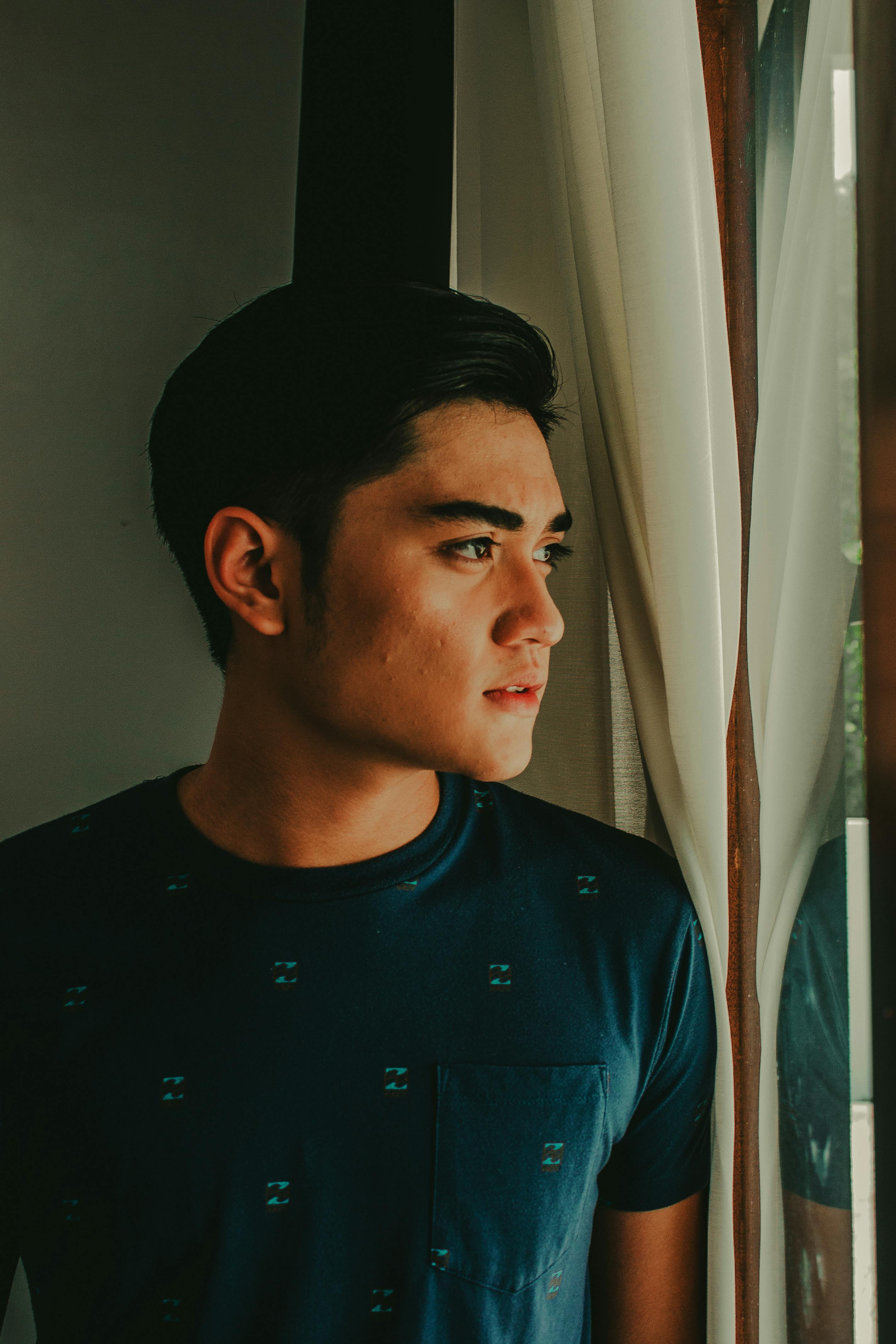 一个年轻人若有所思地凝视着窗外的肖像