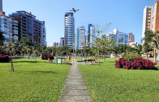 Vibrant urban park with skyscrapers in the background, lush greenery and clear blue sky.