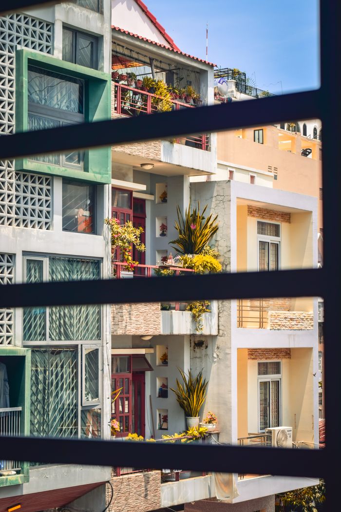 Fachada de edificio con balcones de colores y plantas expuestas al sol