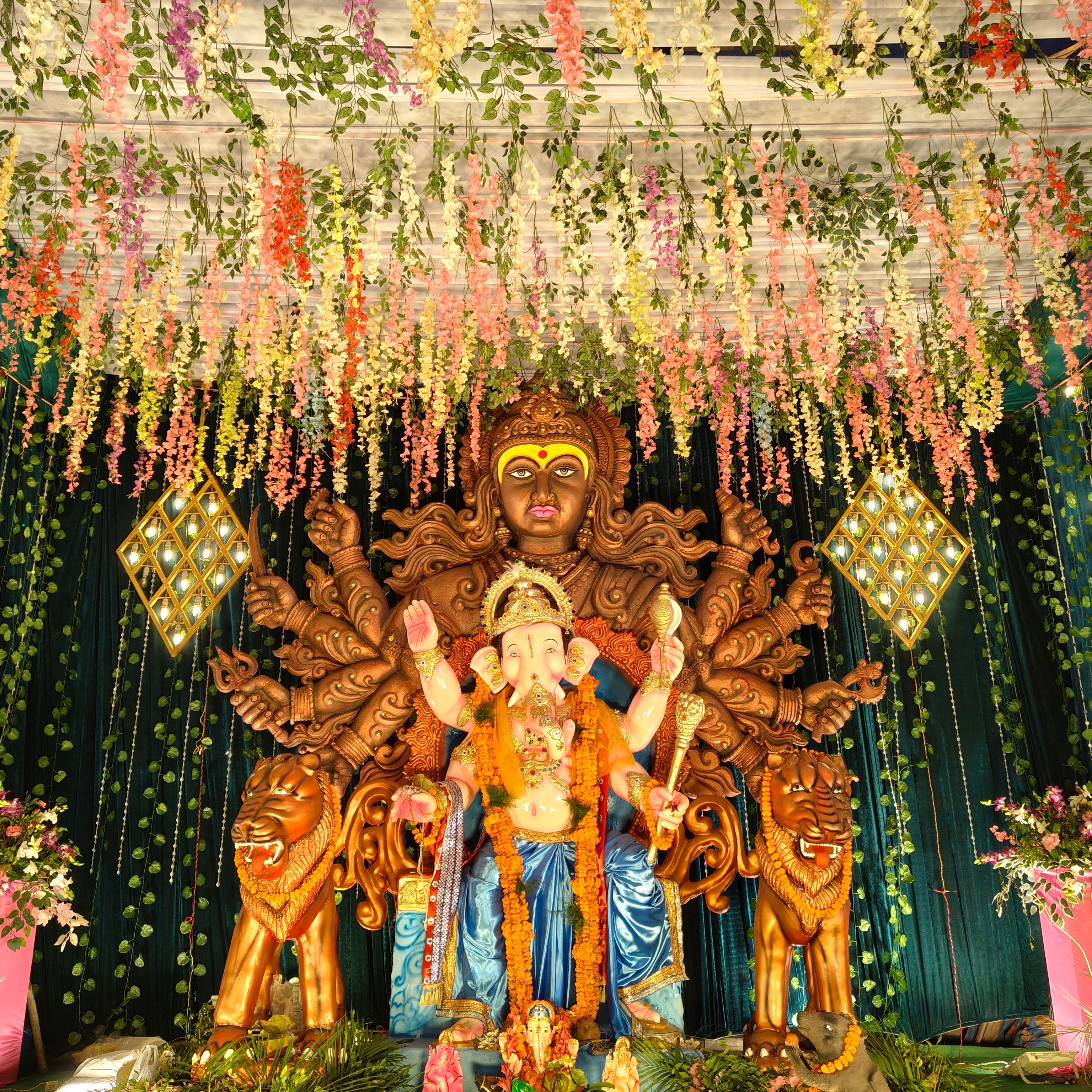 Colorful floral adorned Ganesha idol with intricate decorations during a festival celebration.