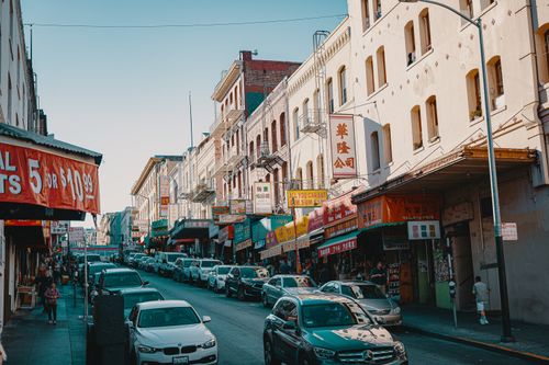 Free Vibrant urban scene in Chinatown featuring shops, signs, and cars in a busy street. Stock Photo