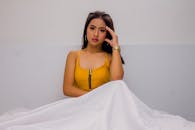 身着黄色上衣的优雅女子在极简主义的环境中若有所思地摆出姿势