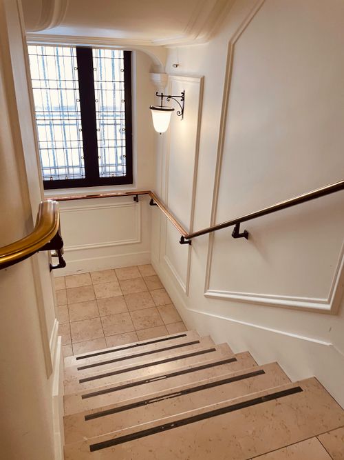 Free Capture of a classic stairwell in Paris with elegant details and warm lighting. Ideal for interior design themes. Stock Photo
