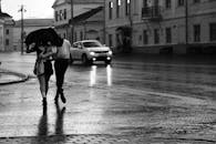 当汽车在雨中驶近时，一对夫妇撑着伞穿过了潮湿的街道