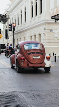 A classic beetle car driving through a city street, capturing urban lifestyle and vintage charm.