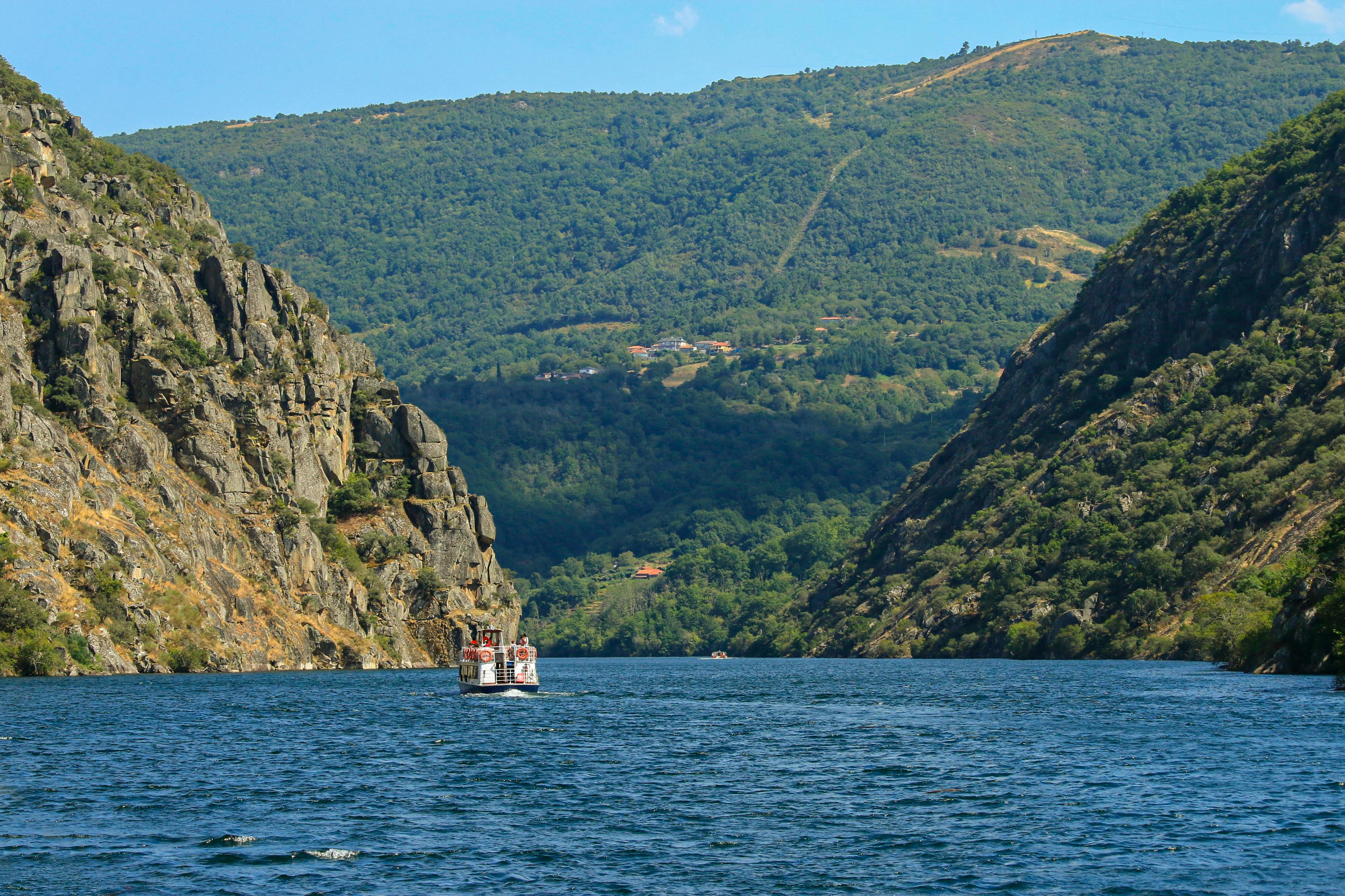 A boat navigates between steep cliffs in the scenic Ribeira Sacra, Galicia, Spain, showcasing stunning natural beauty.