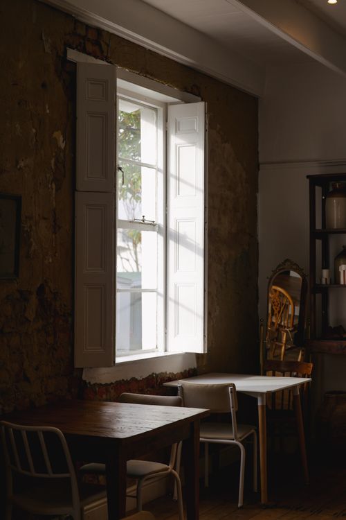 Free Sunlight streams through a window, illuminating a rustic restaurant interior with vintage decor. Stock Photo