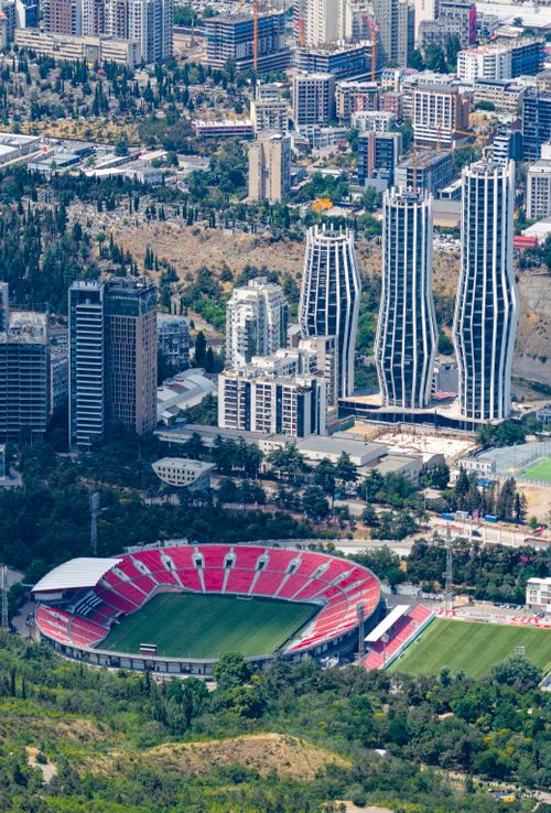 Free A stunning aerial view of Tbilisi featuring modern skyscrapers and a sports stadium, captured in vibrant detail. Stock Photo