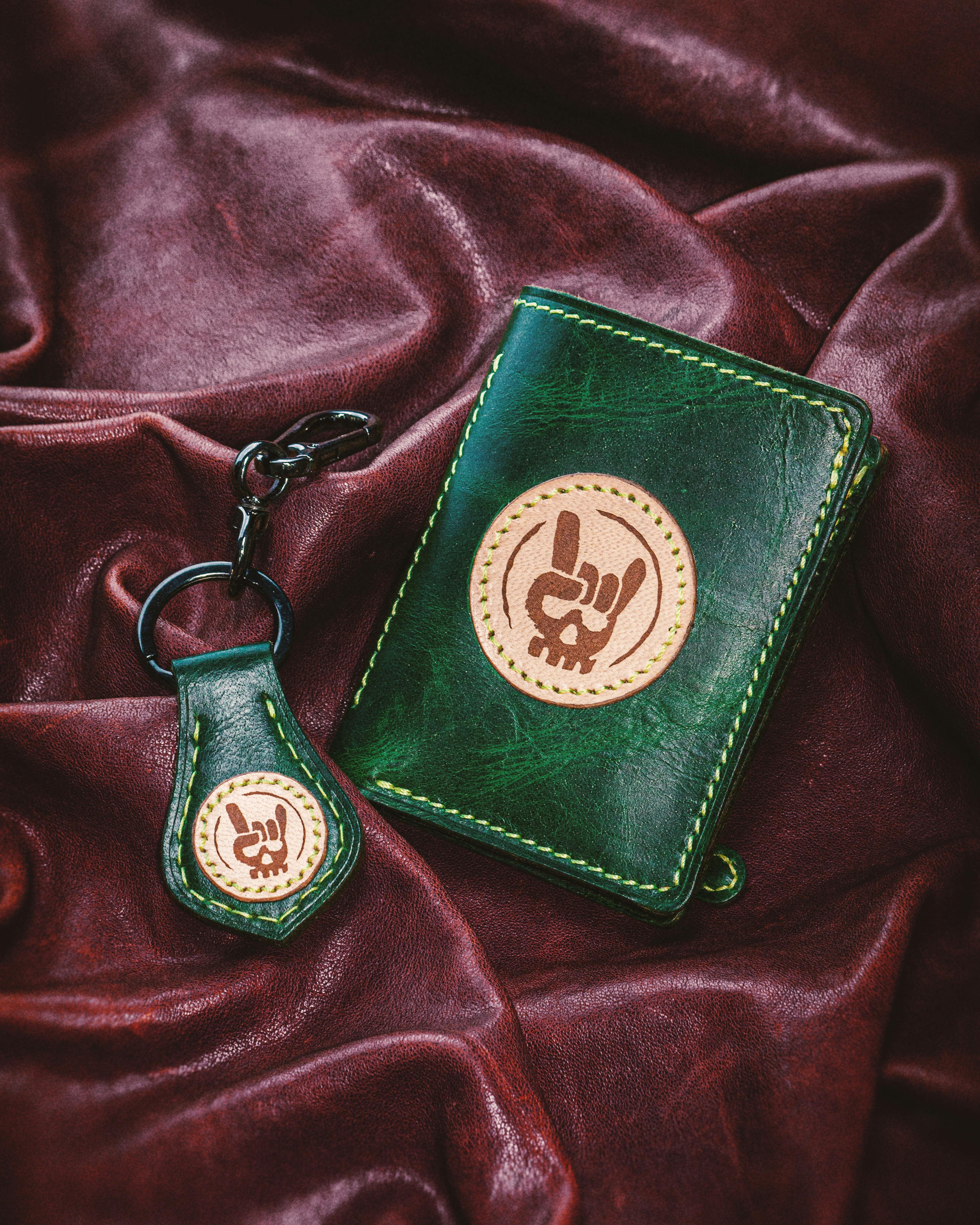 Elegant green leather wallet and keychain featuring unique handmade design on luxurious fabric.