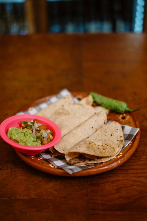 Free Authentic Mexican tacos with guacamole and salsa on a rustic plate, highlighting traditional flavors. Stock Photo