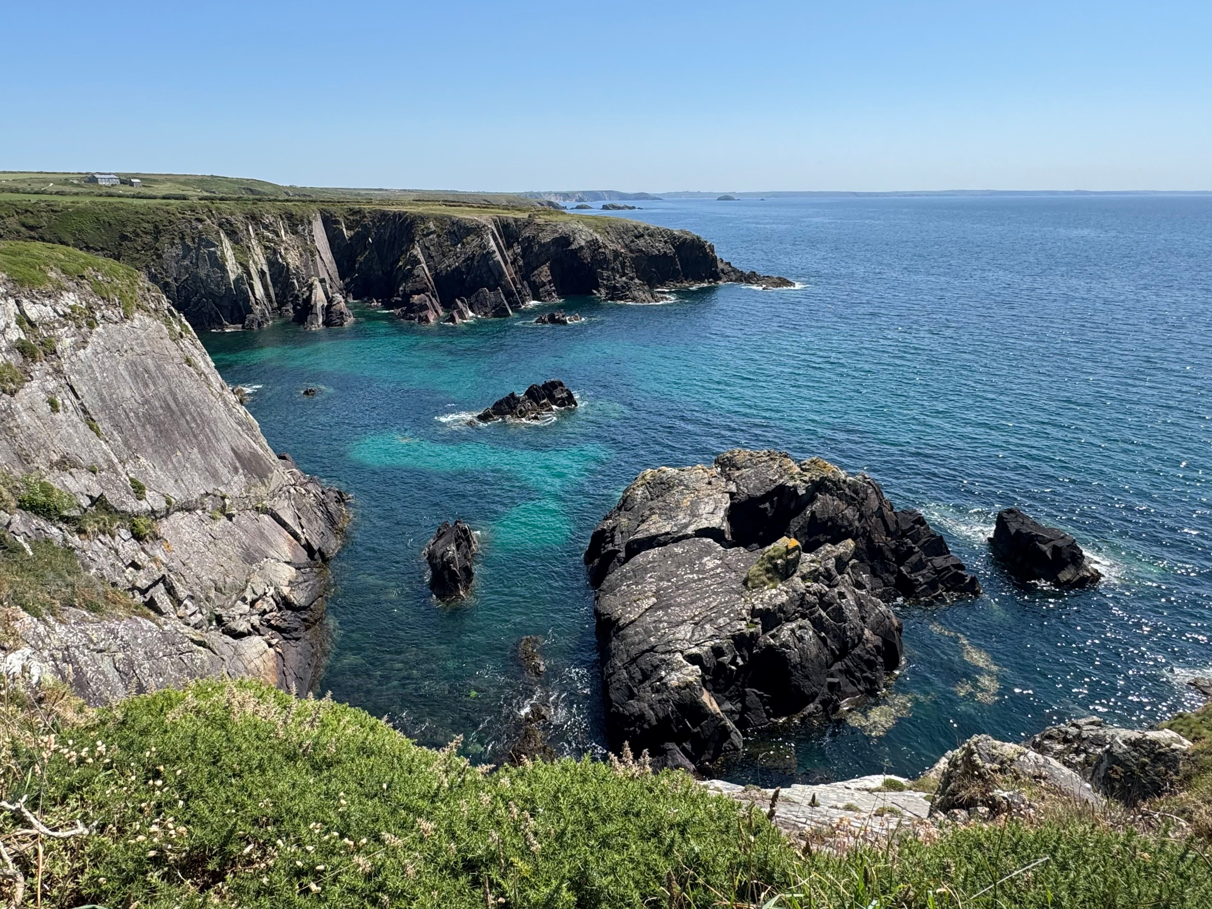 Majestic coastal cliffs and clear blue waters on a sunny day.
