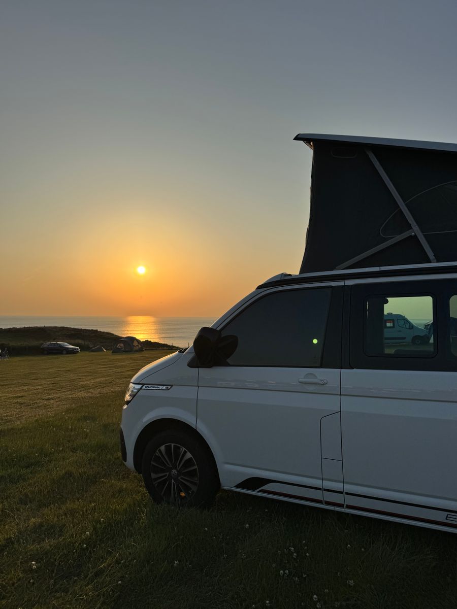 White pop-top camper van with its roof raised at sunset