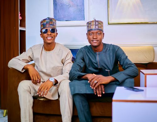 Free Two smiling men wearing traditional Nigerian outfits seated indoors, showcasing cultural fashion. Stock Photo
