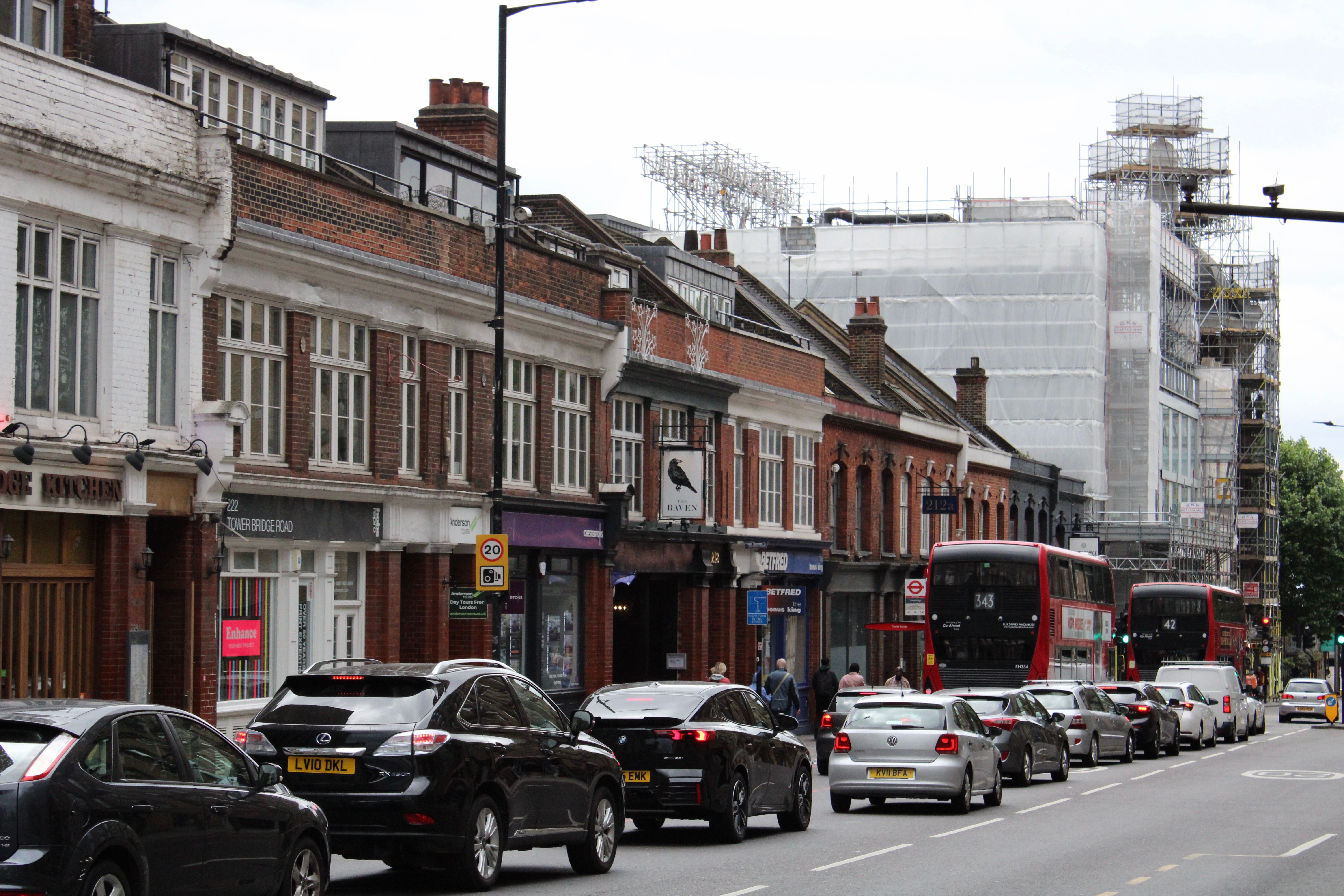 Urban street scene in London featuring traffic with buses and cars on a cloudy day.