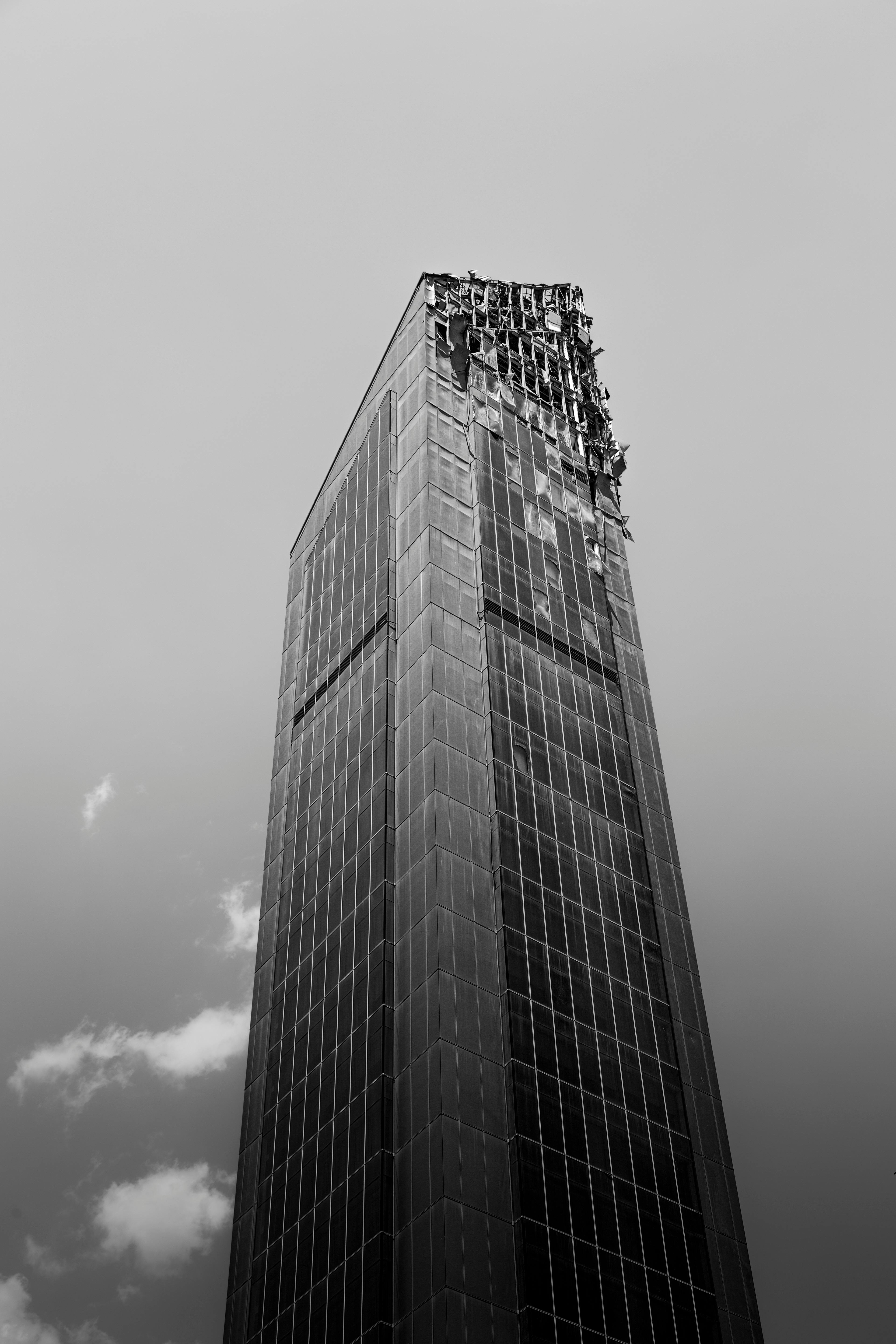 De franc Vista monocroma d'un gratacel malmès amb un fons ennuvolat, que captura la decadència urbana. Foto d'estoc