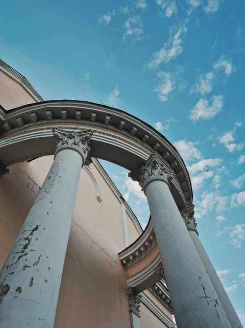 Free Elegant classical columns stand tall against a vibrant blue sky, showcasing timeless architecture. Stock Photo