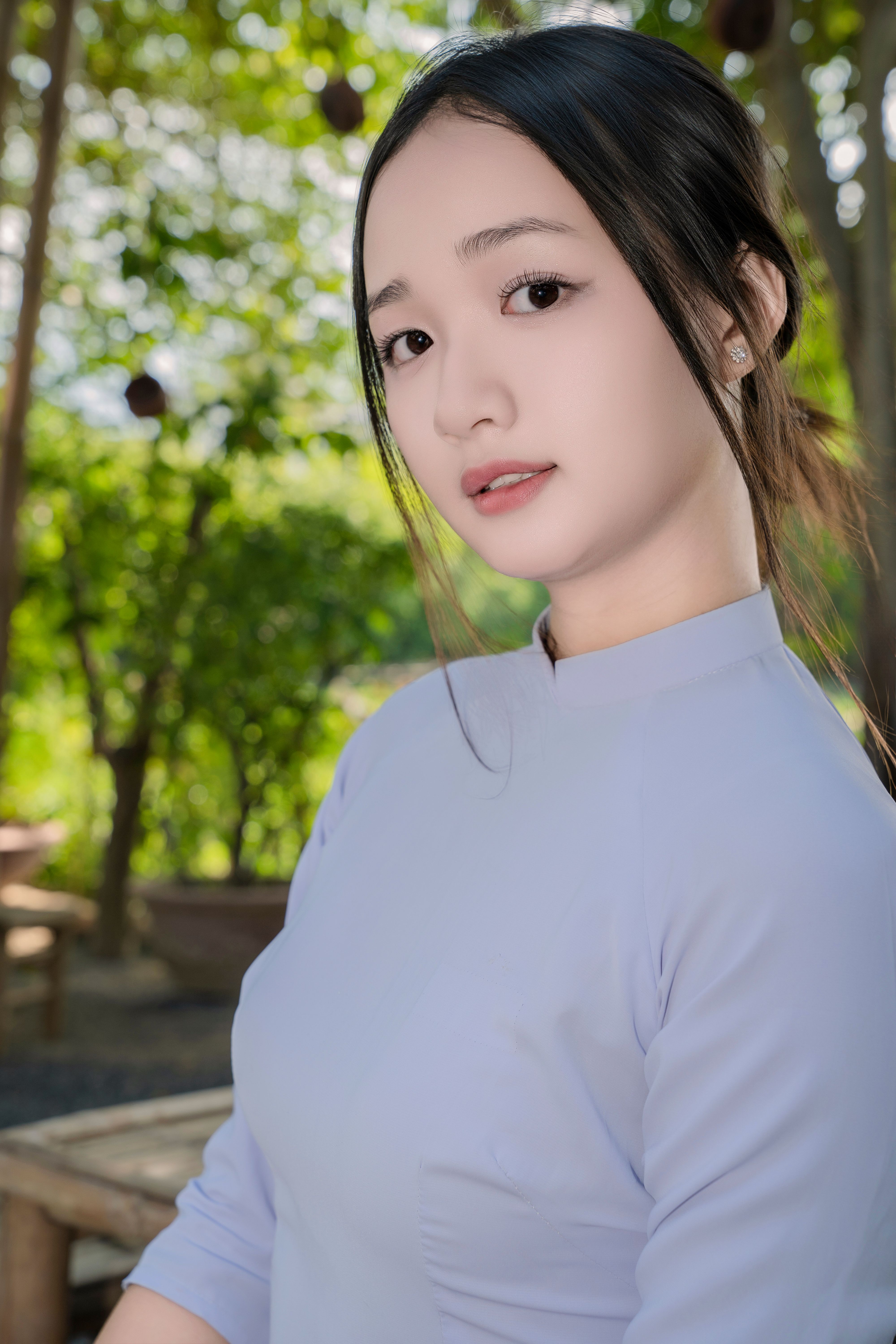 Elegant portrait of a woman in traditional clothing in a serene outdoor setting.