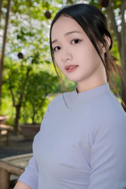 Elegant portrait of a woman in traditional clothing in a serene outdoor setting.