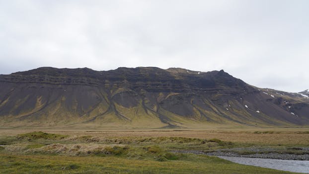 Scenic view of Iceland's rugged mountain landscape under an overcast sky, showcasing natural beauty.
