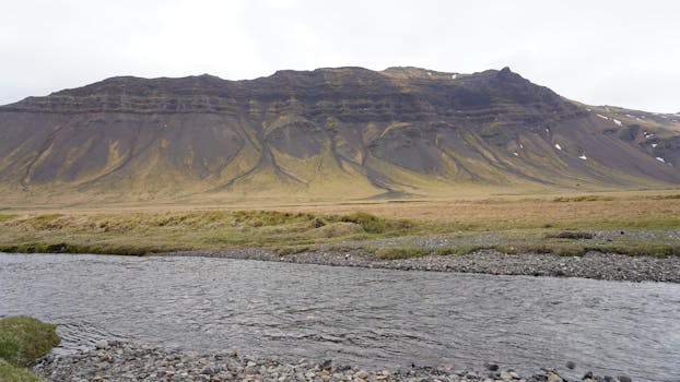 Breathtaking view of Icelandic mountain with river in foreground, showcasing natural beauty.