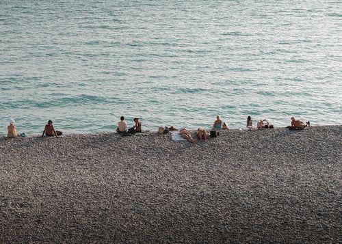 Free People enjoy sunbathing on the pebble beach of Nice, France. A sunny Mediterranean seaside scene. Stock Photo