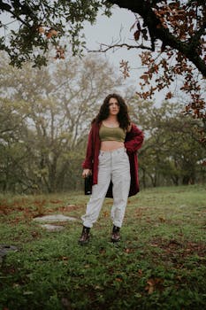 Curly-haired woman in green field holding a wine bottle, artistic mood.