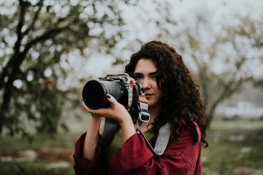 Female photographer outdoors capturing nature with a camera on a foggy day.