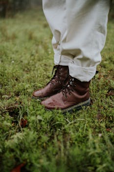 A close-up shot of brown leather boots standing on a grassy surface, perfect for exploring nature.