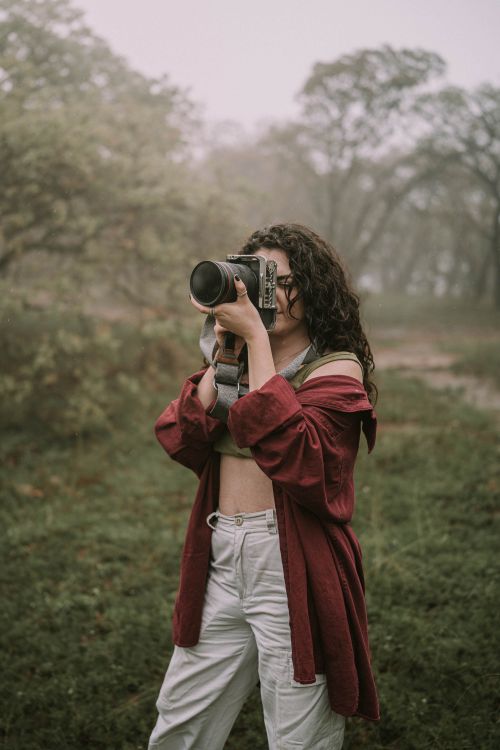 Free A woman photographer takes photos in a foggy forest setting, creating an artistic and serene atmosphere. Stock Photo