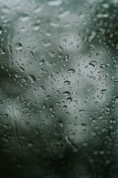 Captivating macro shot of raindrops on a window creating an abstract pattern against a soft-focus background.