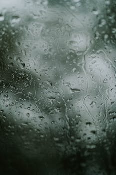 Close-up of rain droplets on a window creating a moody, textured background.